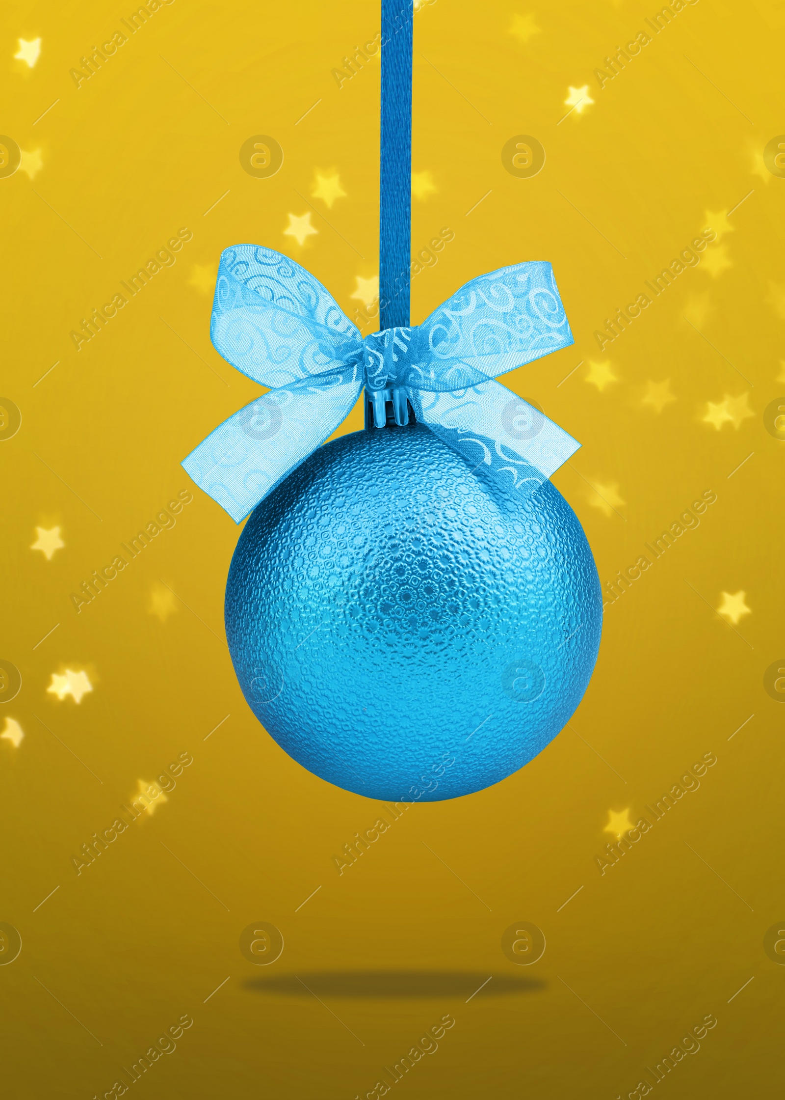 Image of Beautiful blue Christmas ball with bow hanging on yellow background