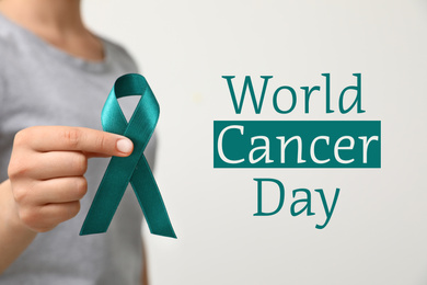 Image of Woman holding green ribbon against light background, closeup. World Cancer Day