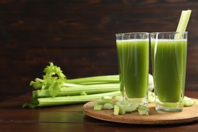 Photo of Glasses of delicious celery juice and vegetables on wooden table. Space for text