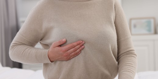 Mammology. Woman doing breast self-examination indoors, closeup