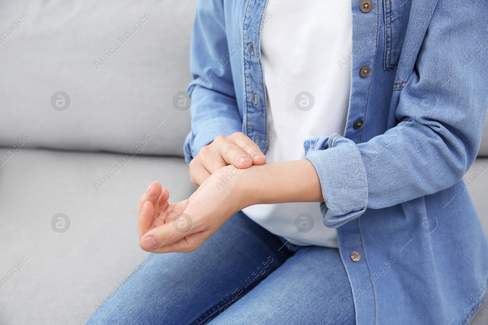 Photo of Young woman checking pulse at home, closeup