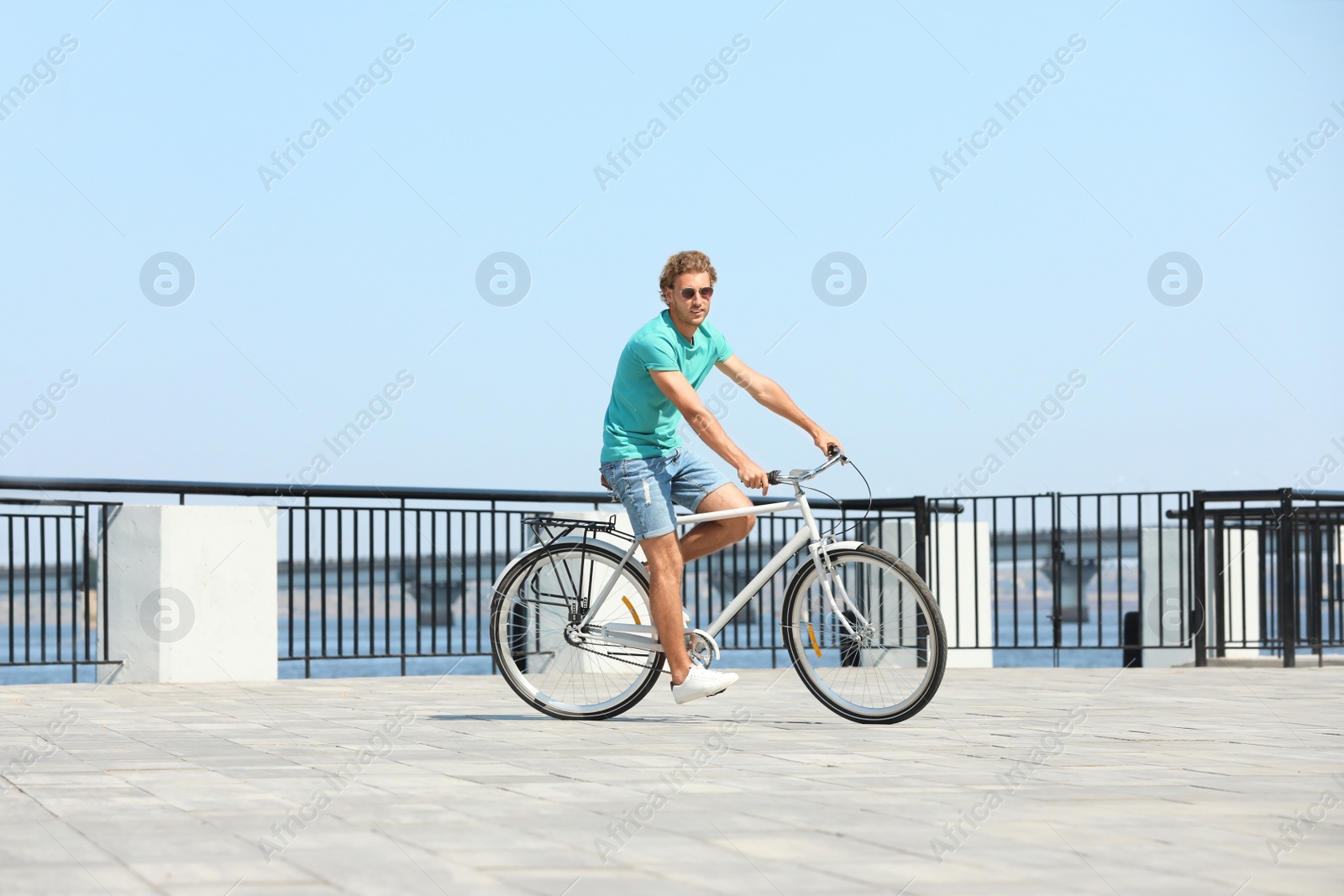 Photo of Handsome young man riding bicycle outdoors on sunny day