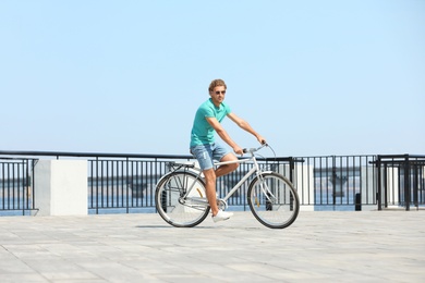 Handsome young man riding bicycle outdoors on sunny day