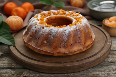 Photo of Homemade yogurt cake with tangerines and powdered sugar on wooden table