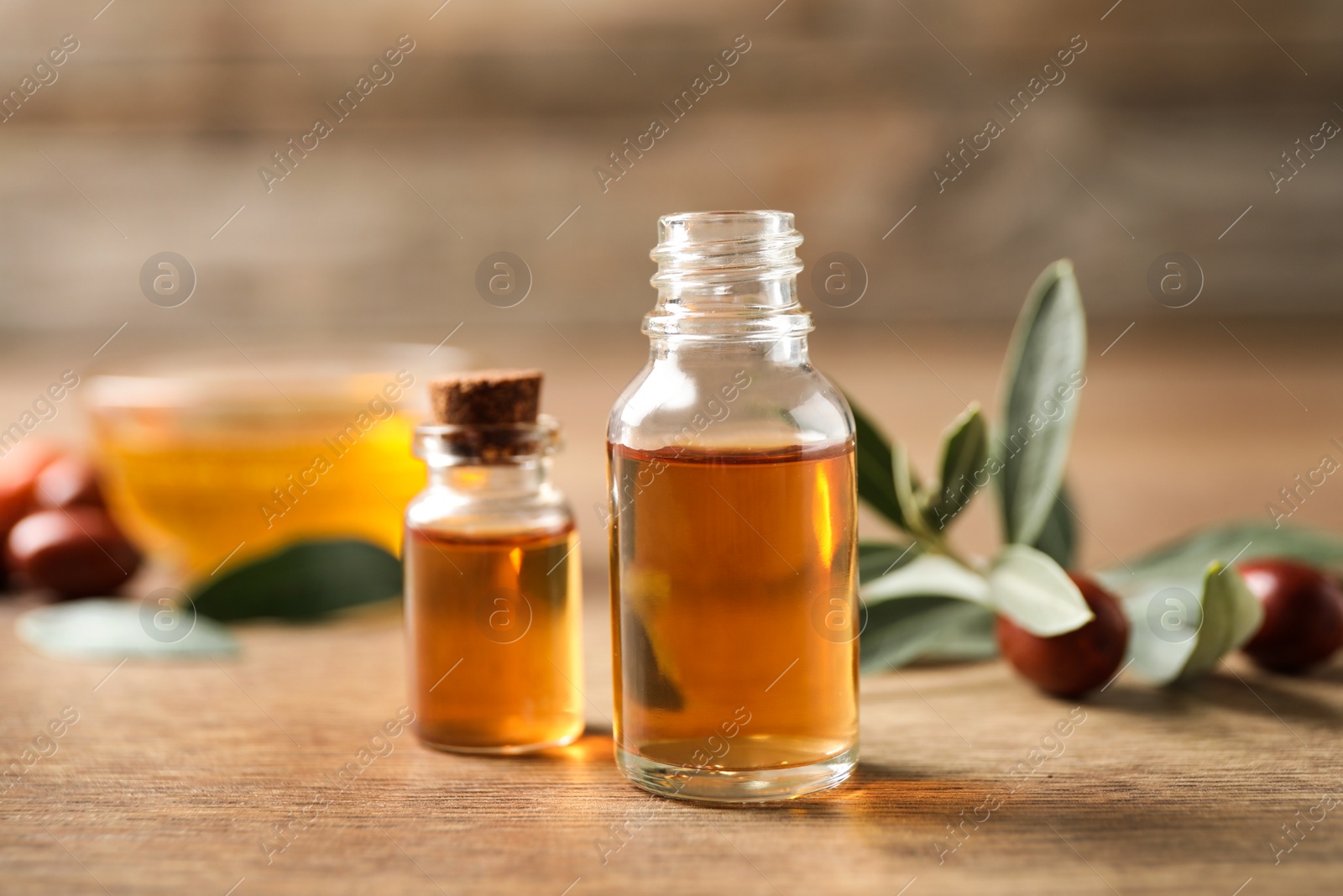 Photo of Glass bottles with jojoba oil on wooden table