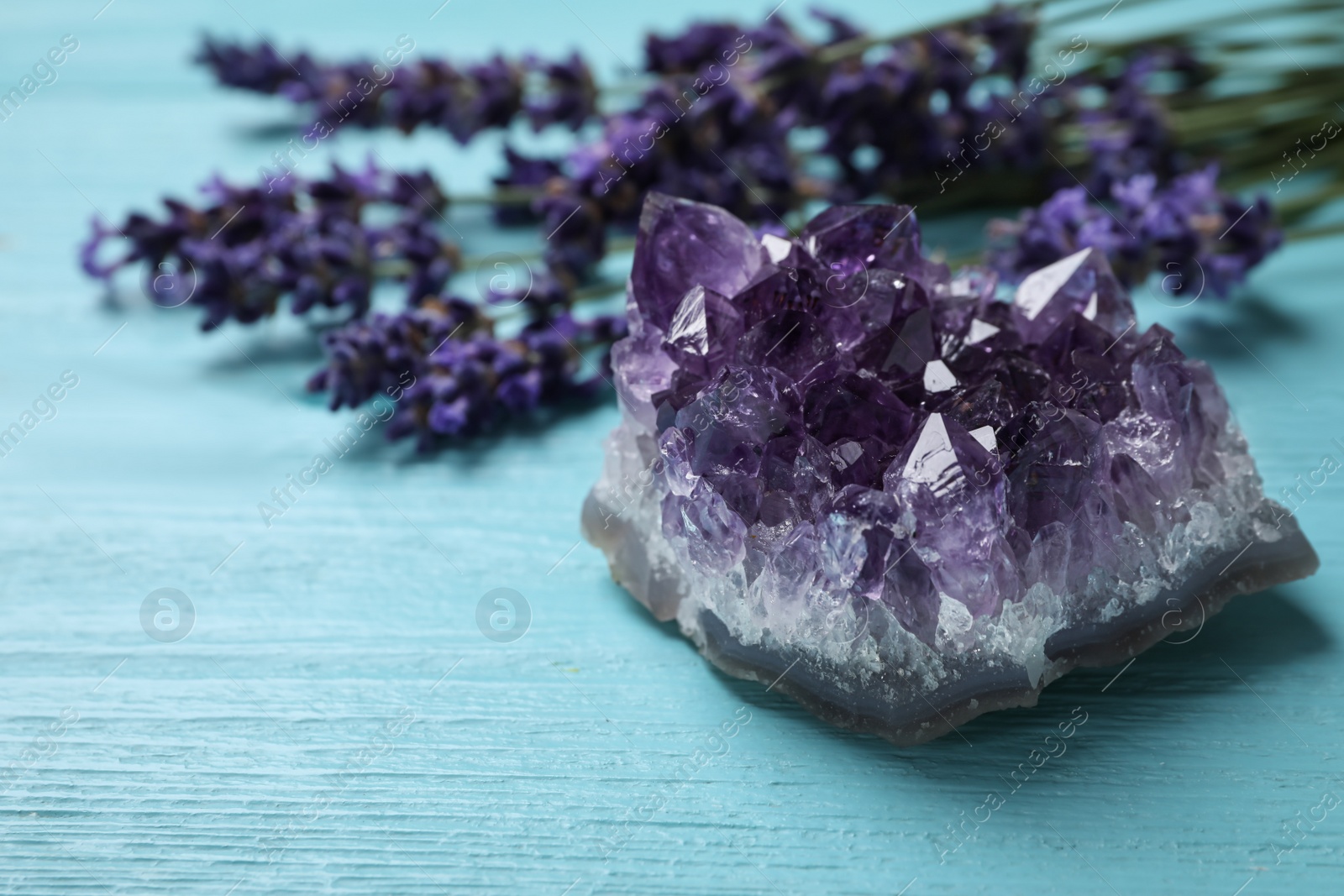 Photo of Amethyst and healing herbs on light blue wooden table, closeup