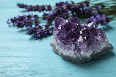 Photo of Amethyst and healing herbs on light blue wooden table, closeup