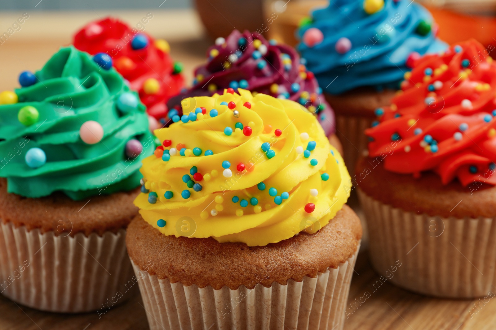 Photo of Delicious cupcakes with colorful cream and sprinkles, closeup