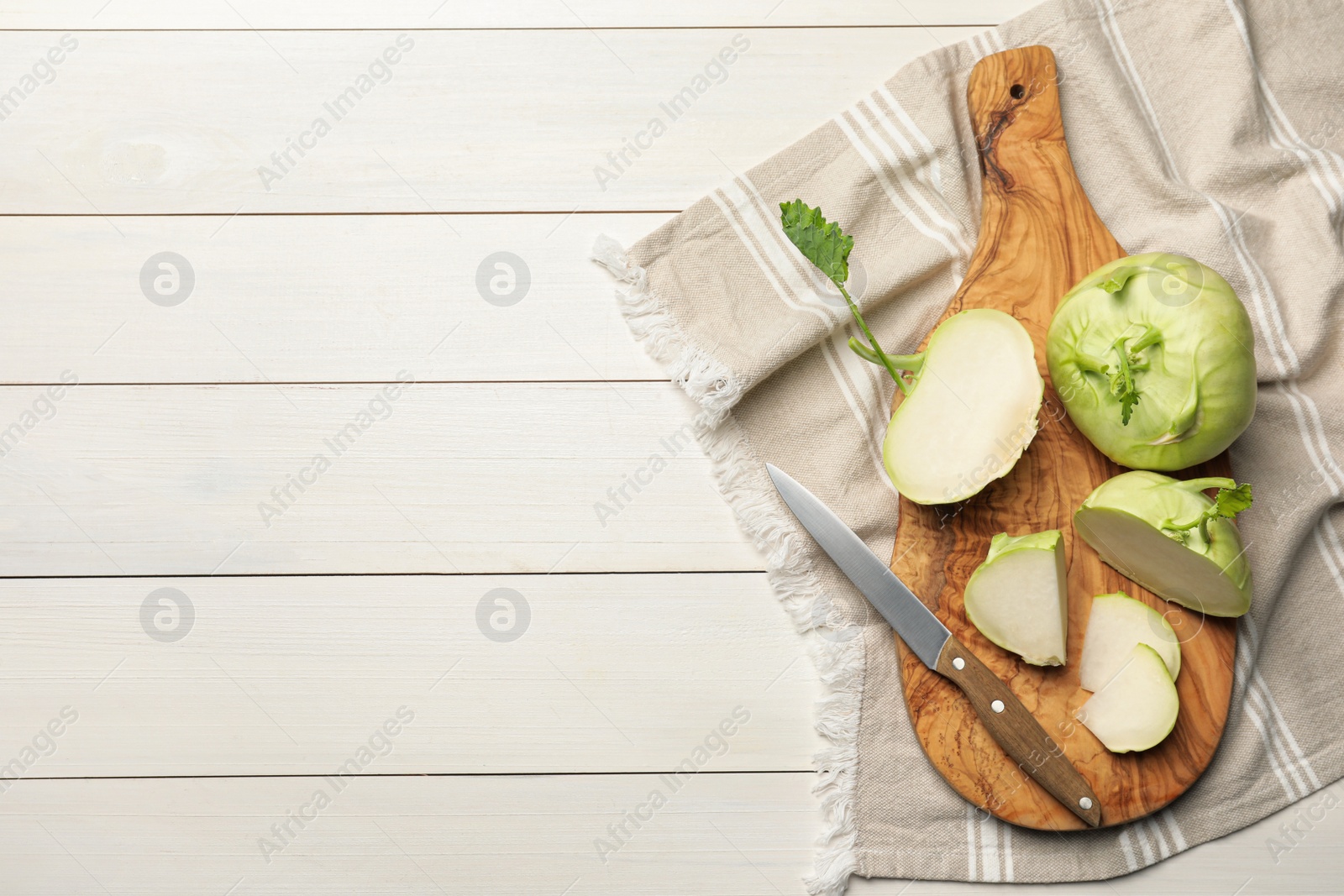 Photo of Whole and cut kohlrabi plants on white wooden table, flat lay. Space for text