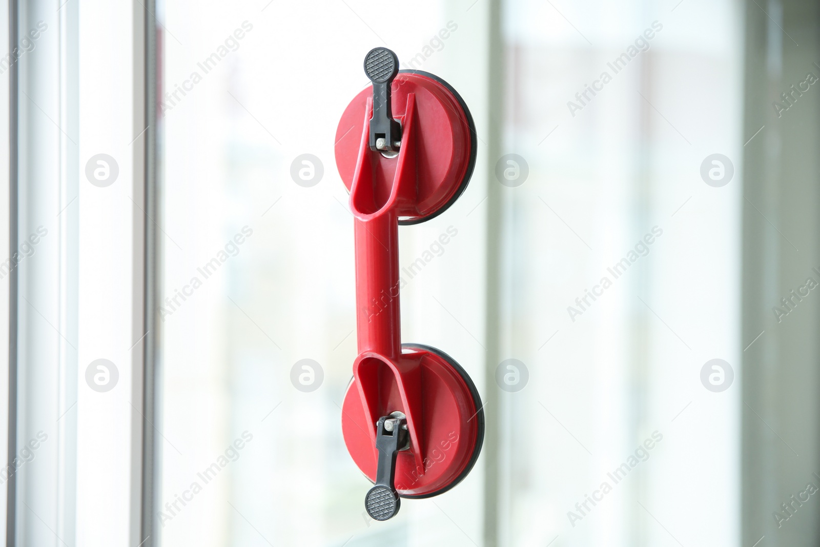 Photo of Suction lifter on glass against blurred background. Window installation