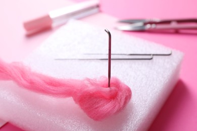 Photo of Felting mat, needles and wool on pink background, closeup