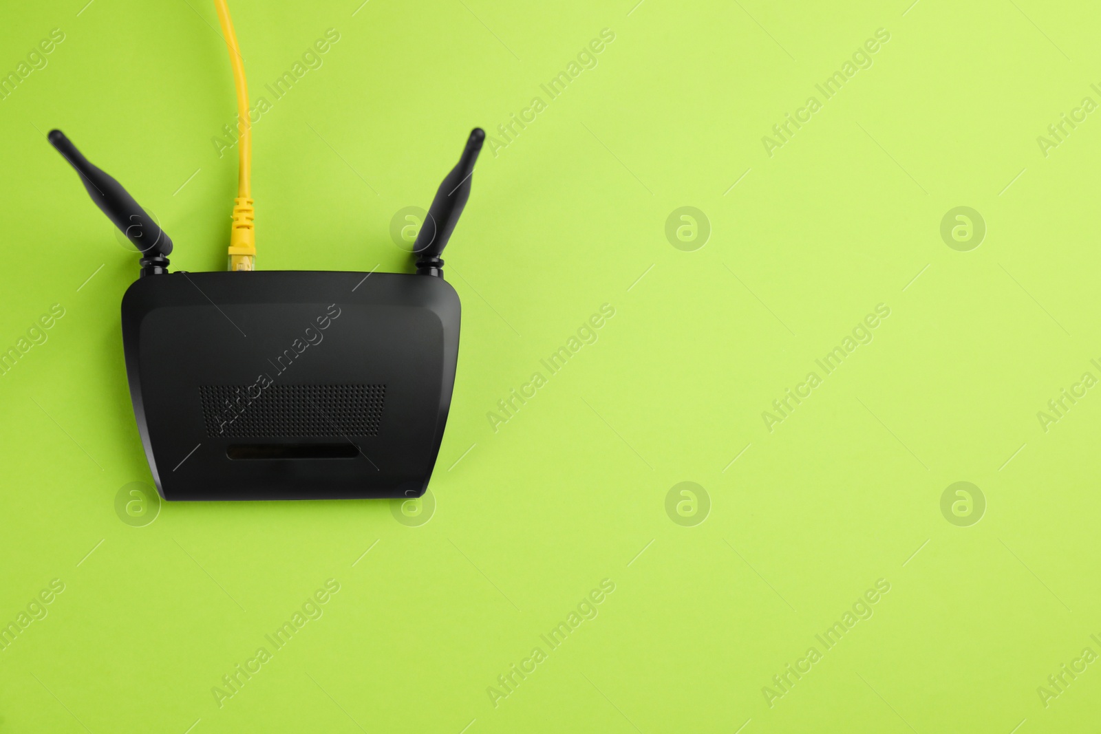 Photo of Modern Wi-Fi router on green background, top view. Space for text