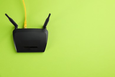 Modern Wi-Fi router on green background, top view. Space for text