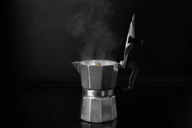Photo of Moka pot with hot brewed coffee on stove