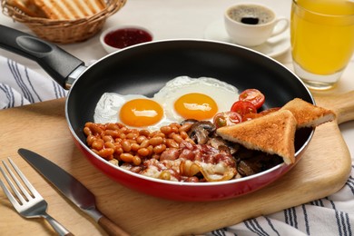 Photo of Frying pan with cooked traditional English breakfast on table, closeup