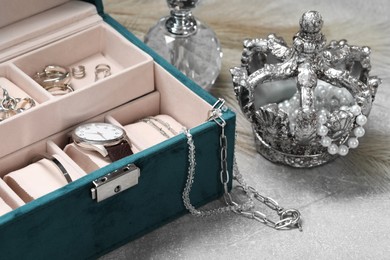Photo of Jewelry box with many different accessories, perfume and decor on light grey table, closeup