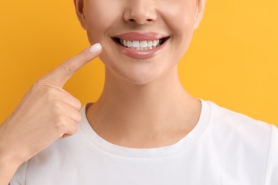 Woman showing her clean teeth and smiling on yellow background, closeup