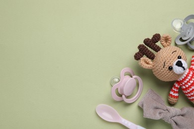 Photo of Flat lay composition with pacifiers and other baby stuff on pale green background. Space for text
