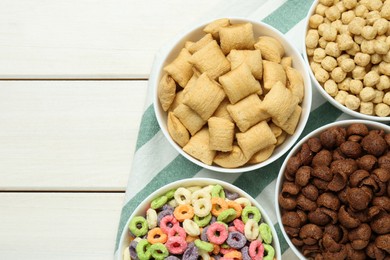 Different delicious breakfast cereals on white wooden table, flat lay. Space for text