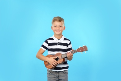 Photo of Portrait of little boy playing guitar on color background