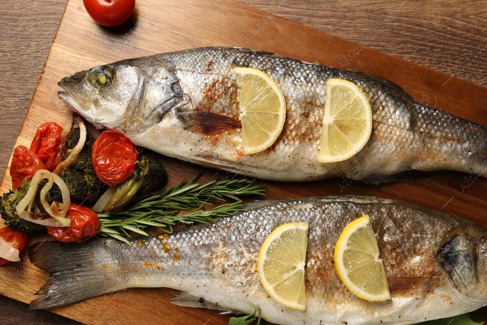 Photo of Delicious baked fish and vegetables on wooden table, top view