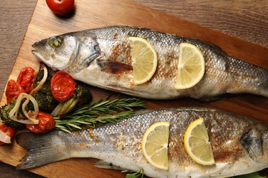 Delicious baked fish and vegetables on wooden table, top view