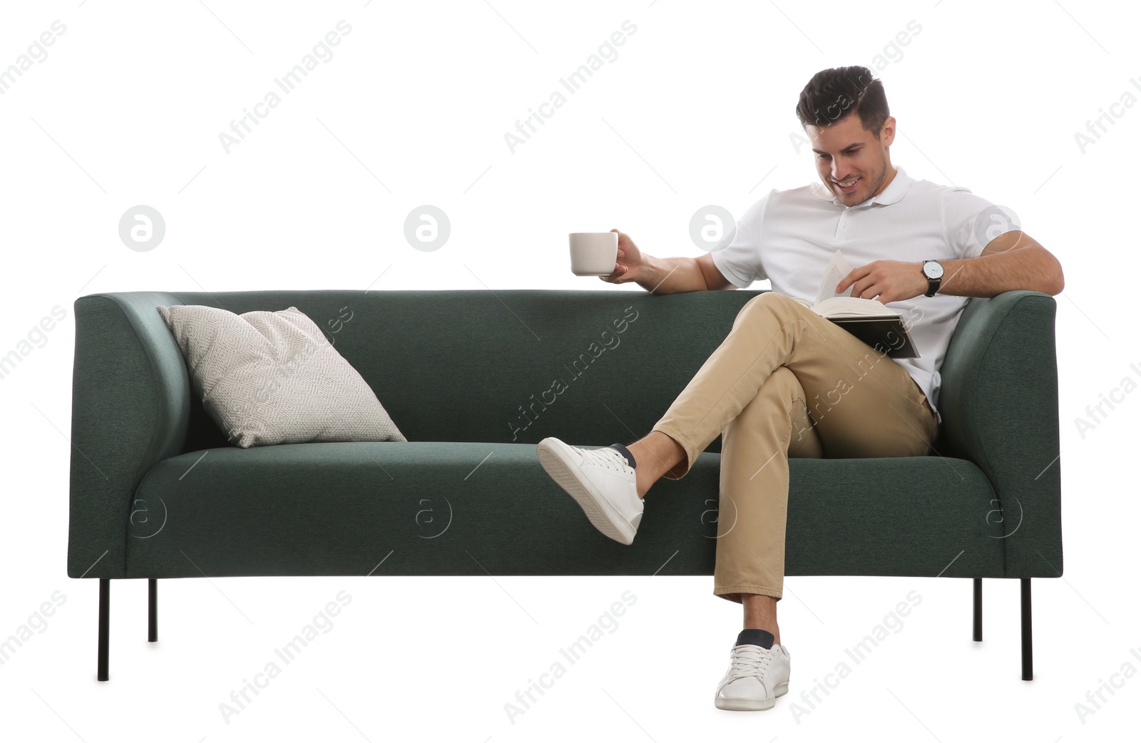 Photo of Man with cup of drink and book on comfortable green sofa against white background