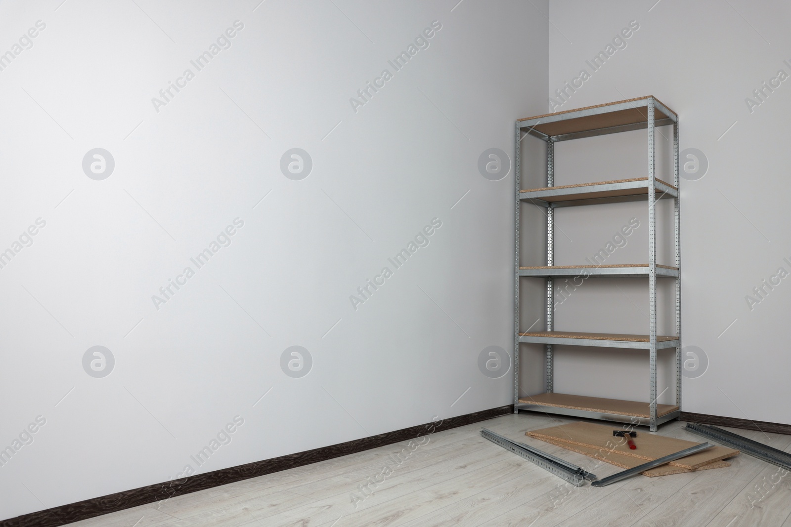Photo of Office room with white walls and metal storage shelf. Space for text