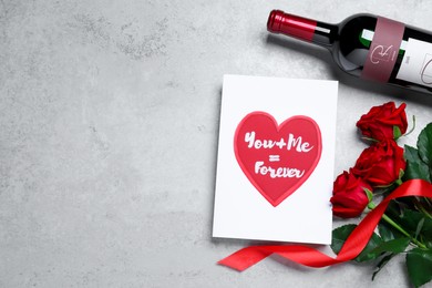 Photo of Marvelous message of love with red roses and wine on grey table, flat lay. Space for text