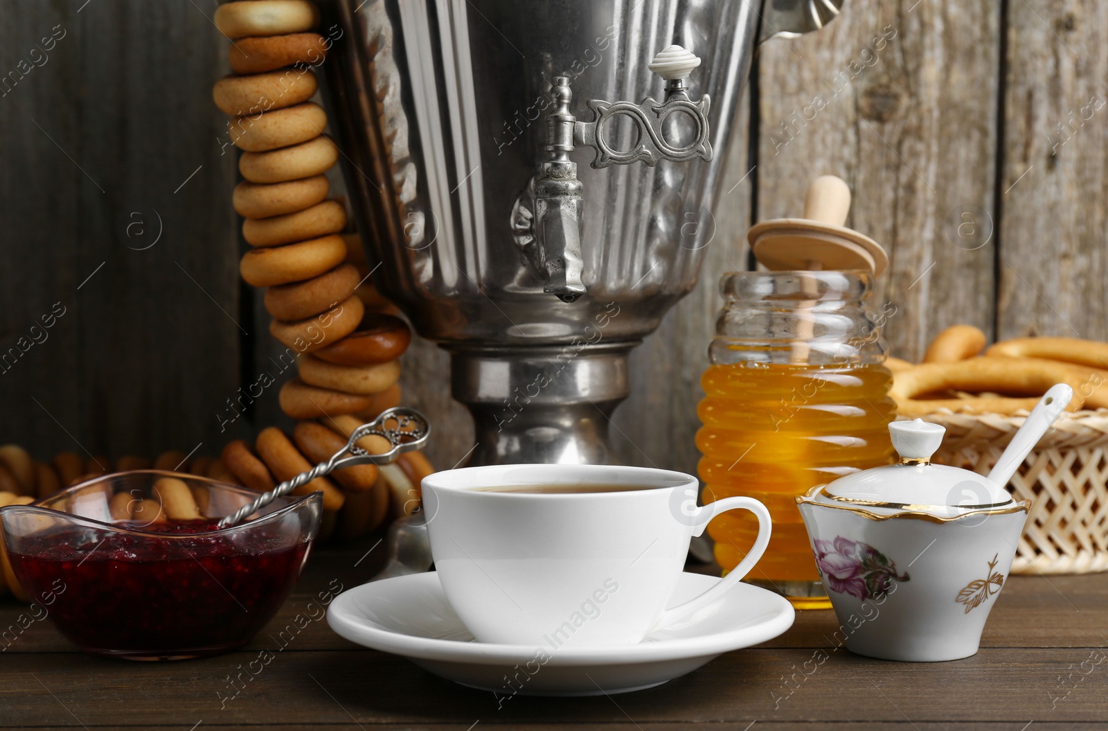 Photo of Composition with hot tea and delicious ring shaped Sushki (dry bagels) on wooden table