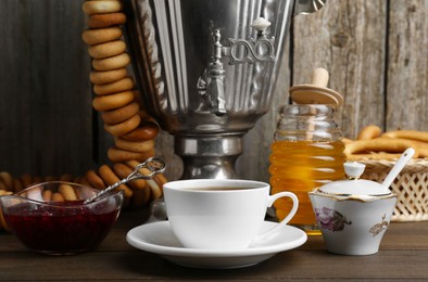 Photo of Composition with hot tea and delicious ring shaped Sushki (dry bagels) on wooden table