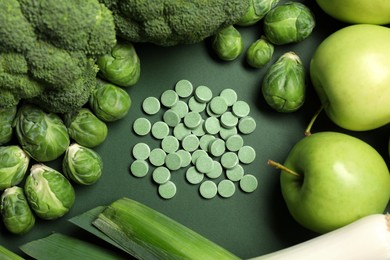 Photo of Pile of pills and food on green background, flat lay. Prebiotic supplements