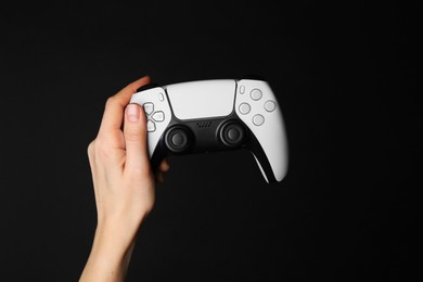 Photo of Woman holding game controller on black background, closeup