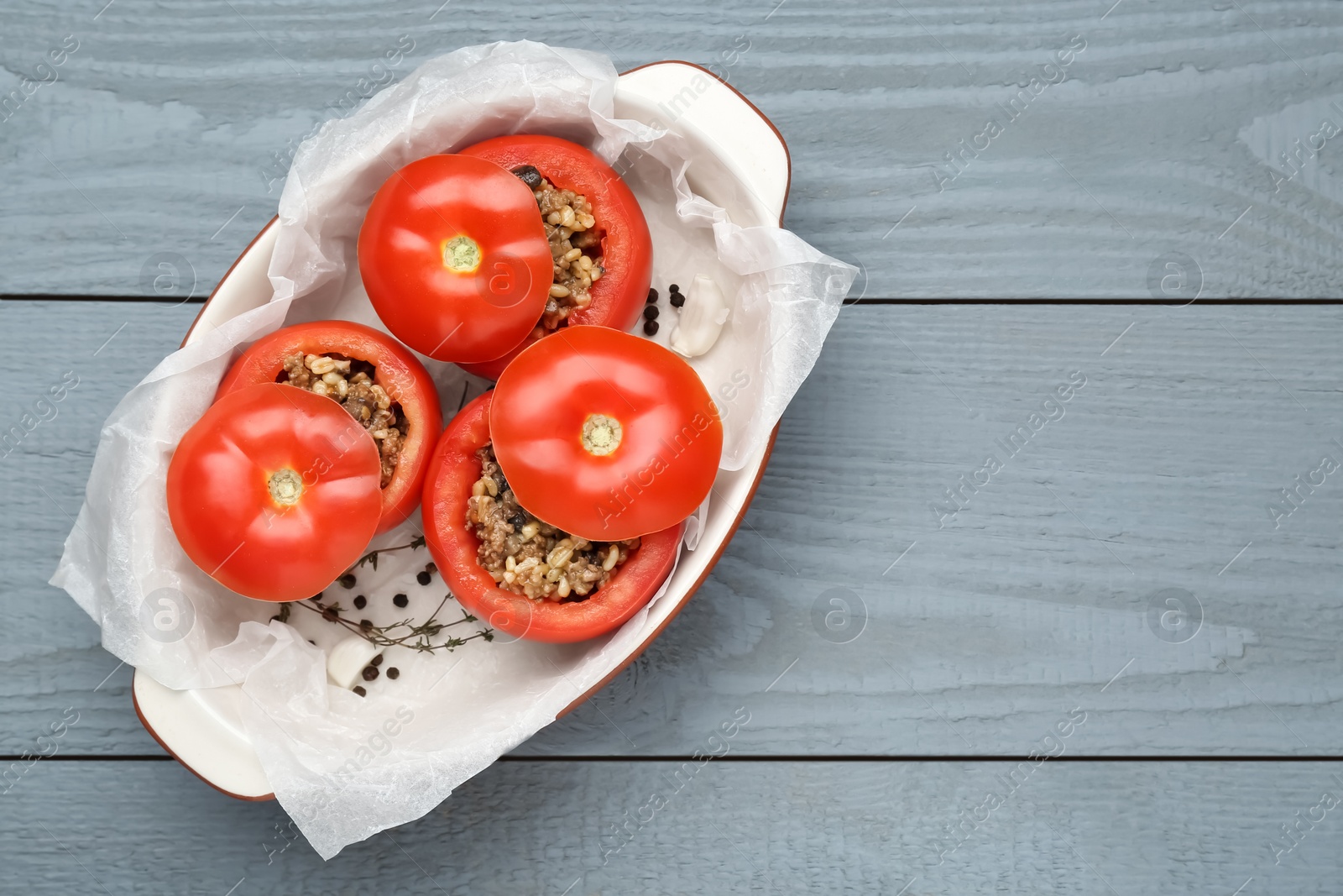 Photo of Uncooked stuffed tomatoes with minced beef, bulgur and mushrooms in baking dish on grey wooden table, top view. Space for text