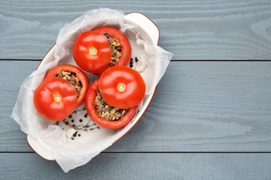 Photo of Uncooked stuffed tomatoes with minced beef, bulgur and mushrooms in baking dish on grey wooden table, top view. Space for text