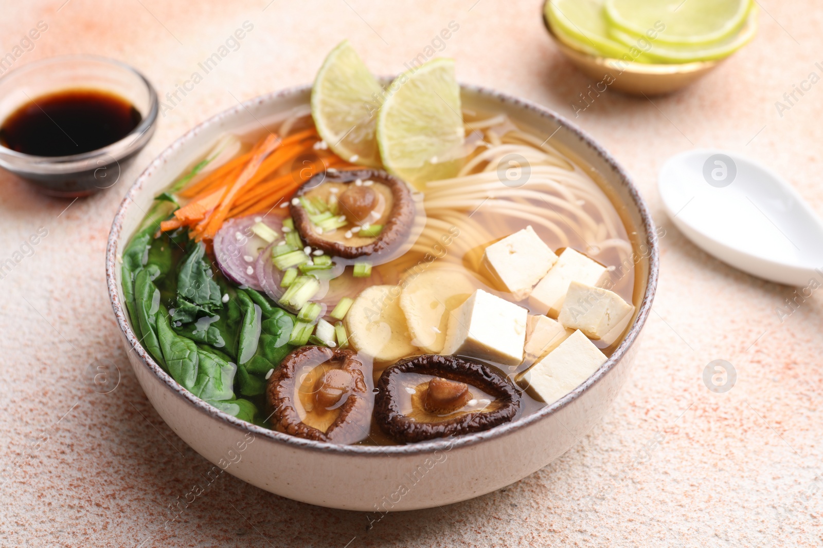 Photo of Bowl of vegetarian ramen served on color textured table, closeup