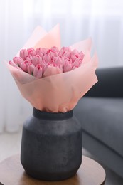 Bouquet of beautiful pink tulips in vase on wooden table indoors