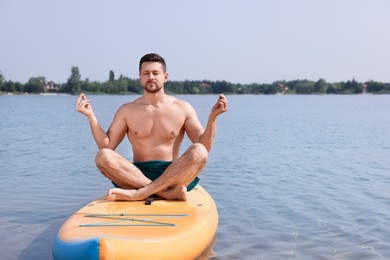 Photo of Man practicing yoga on SUP board on river, space for text