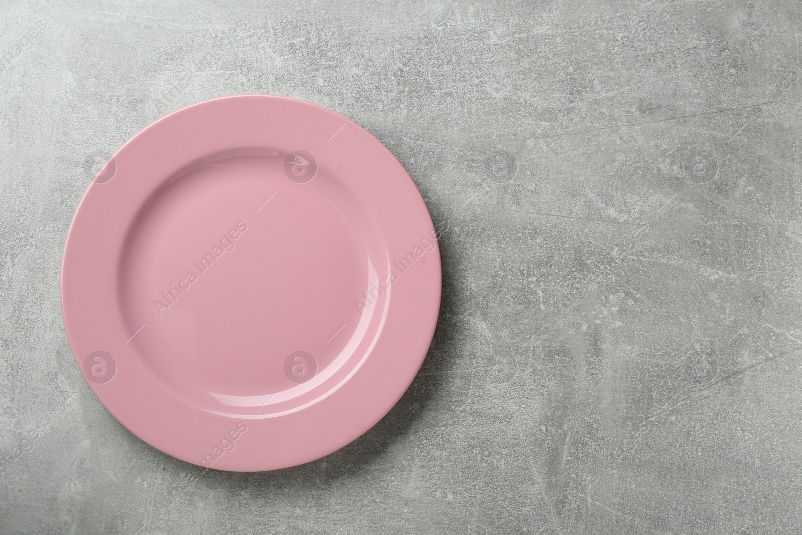 Photo of Clean pink plate on grey table, top view. Space for text