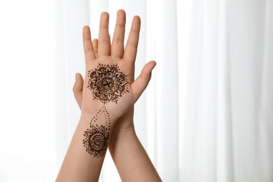 Little girl with henna tattoo on palm, closeup and space for text. Traditional mehndi ornament