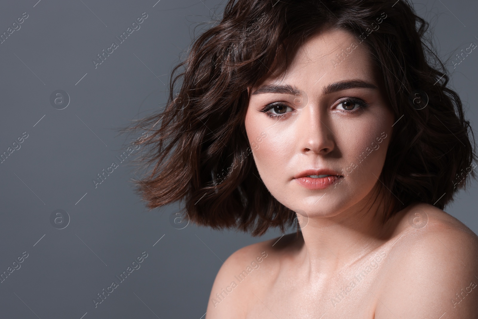 Photo of Portrait of beautiful young woman with wavy hairstyle on grey background. Space for text