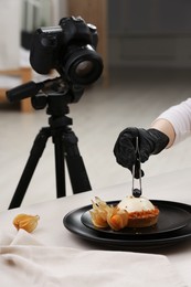 Photo of Food stylist creating beautiful composition with delicious dessert on white wooden table in photo studio, closeup
