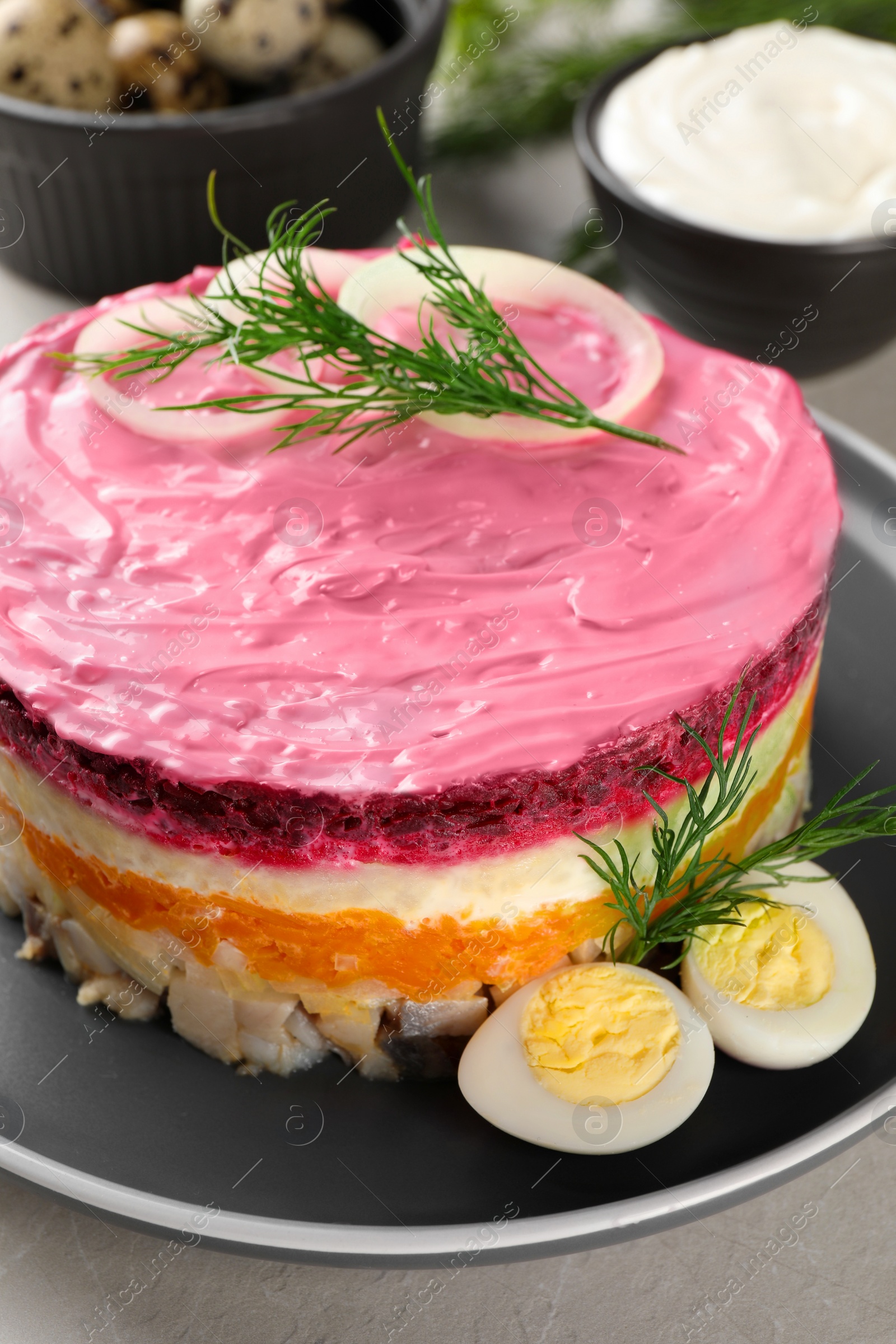 Photo of Herring under fur coat salad on light grey table, closeup. Traditional Russian dish