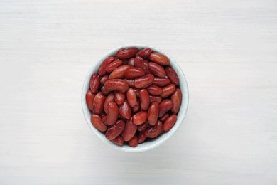 Photo of Bowl of canned kidney beans on white wooden table, top view