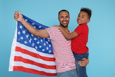 Photo of 4th of July - Independence Day of USA. Happy man and his son with American flag on light blue background
