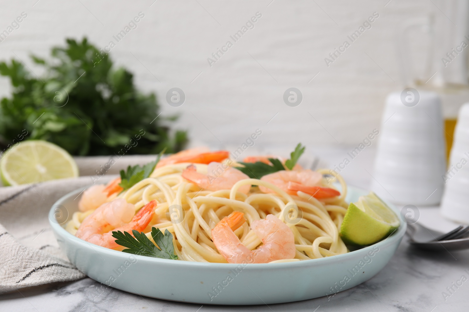 Photo of Tasty spaghetti with shrimps, lime and parsley on white marble table, closeup