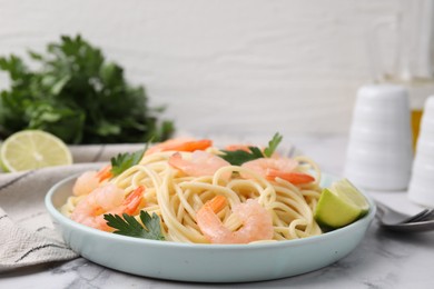 Photo of Tasty spaghetti with shrimps, lime and parsley on white marble table, closeup