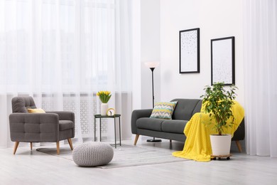 Spring atmosphere. Stylish living room interior with comfortable furniture and bouquet of beautiful yellow tulips