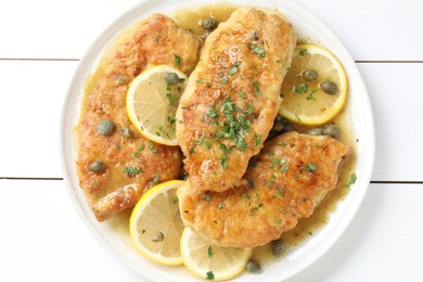 Delicious chicken piccata on white wooden table, top view