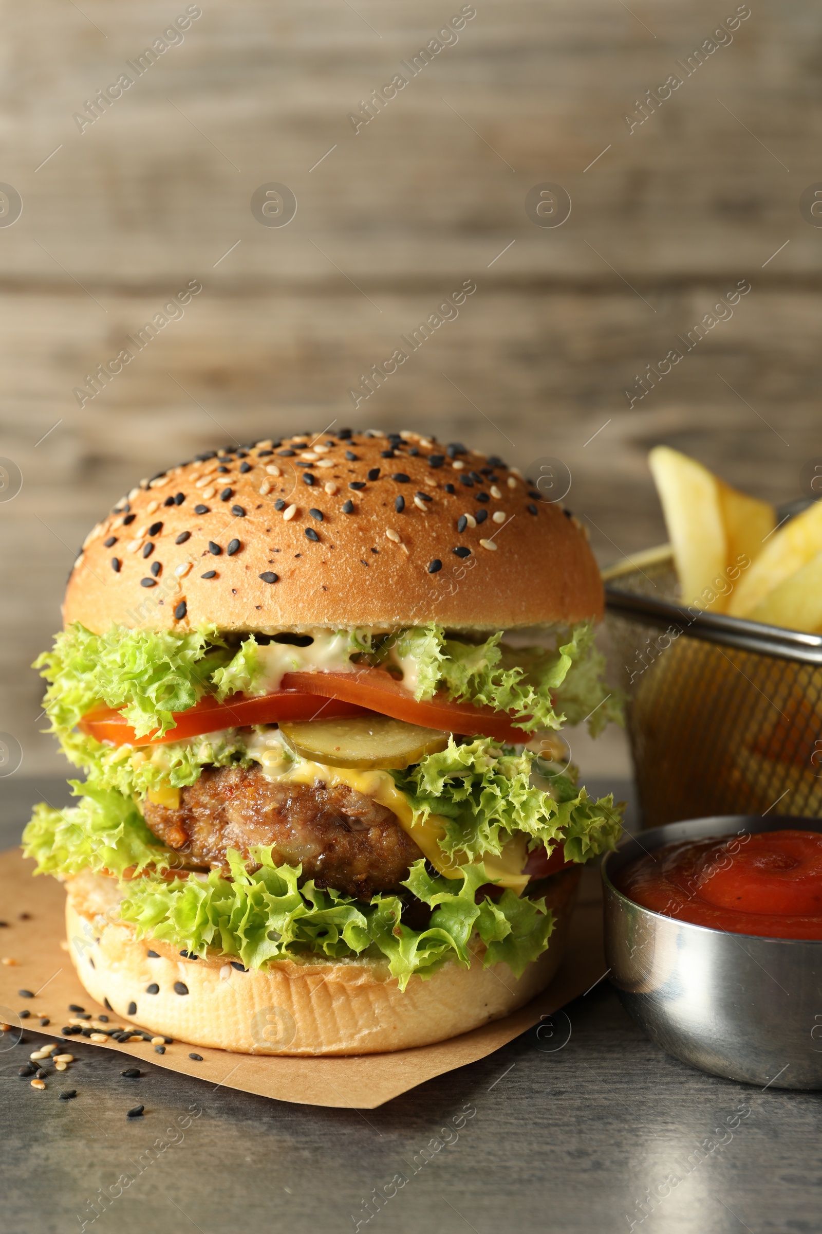 Burger with delicious patty, french fries and sauce on gray table Photo of Burger with delicious patty, french fries and sauce on gray table